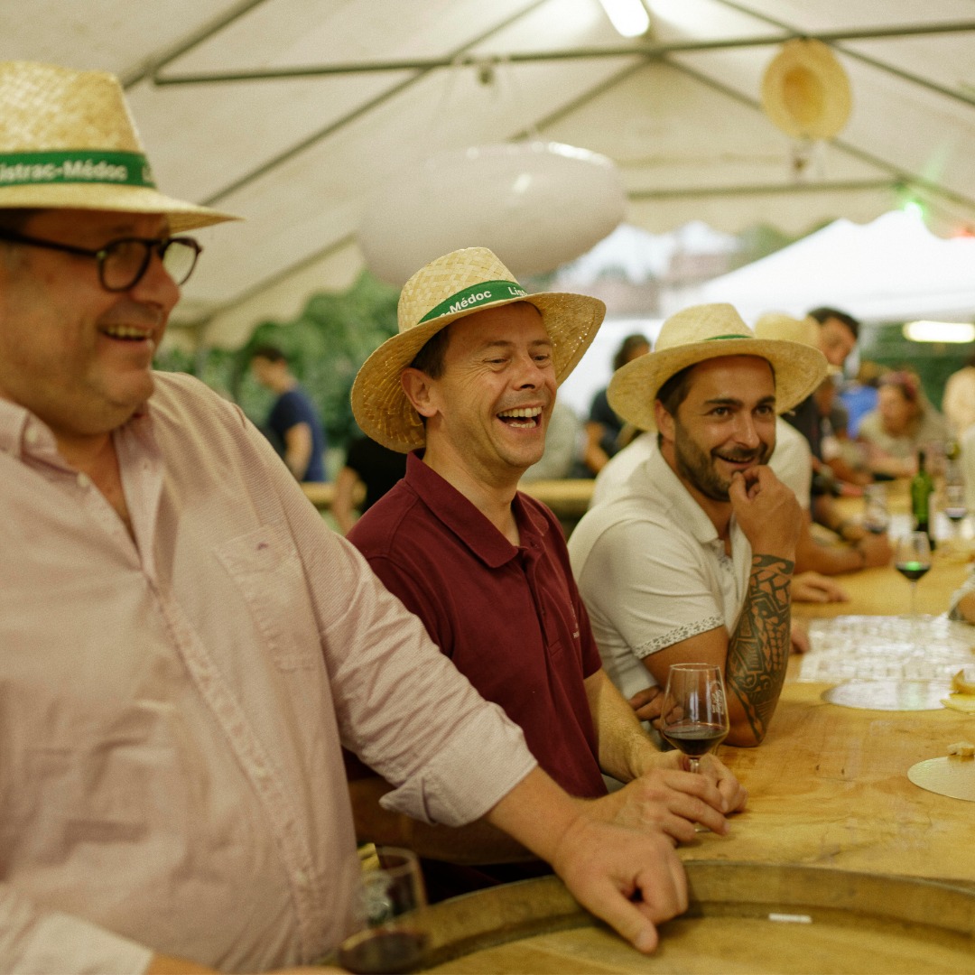 Viticulteurs sous un barnum en train de rire et servir des festivaliers