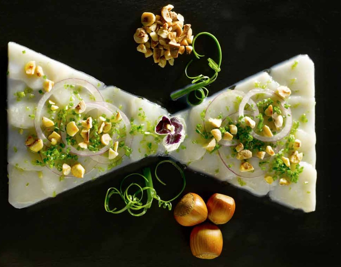 Photo d'un carpaccio de saint jacques et noisette torréfiées en forme de noeud de papillons