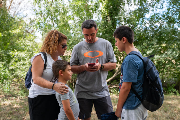 une famille regardant le téléphone tenu dans les mains du papa