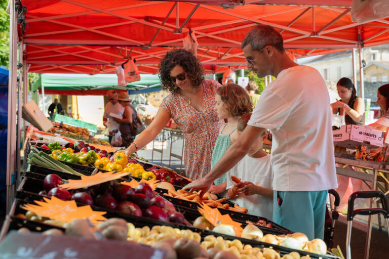 Famille devant des étals de fruits et légumes