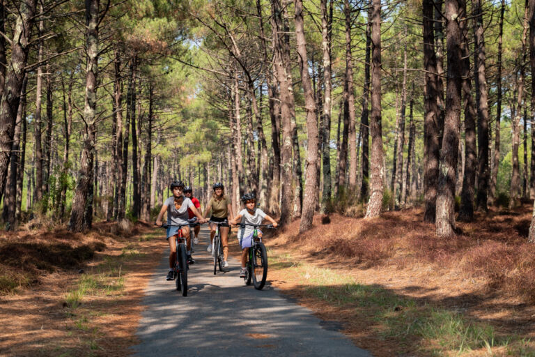 famille de face faisant du vélo sur piste cyclable du Porge en gironde
